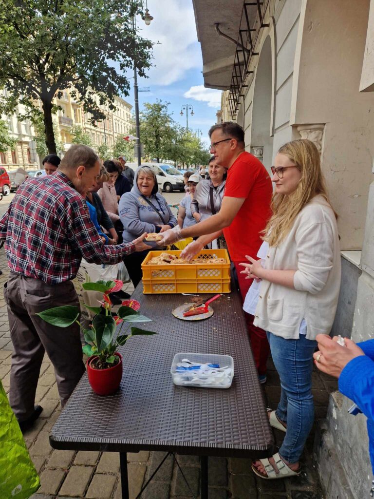 zdjęcie przedstawia wolontariuszy pracujących na rzecz potrzebujących przy wydawaniu żywności przed Jadłodzielnią wsólna spiżarnia w Bydgoszczy. Fundacja Chcepomagam.